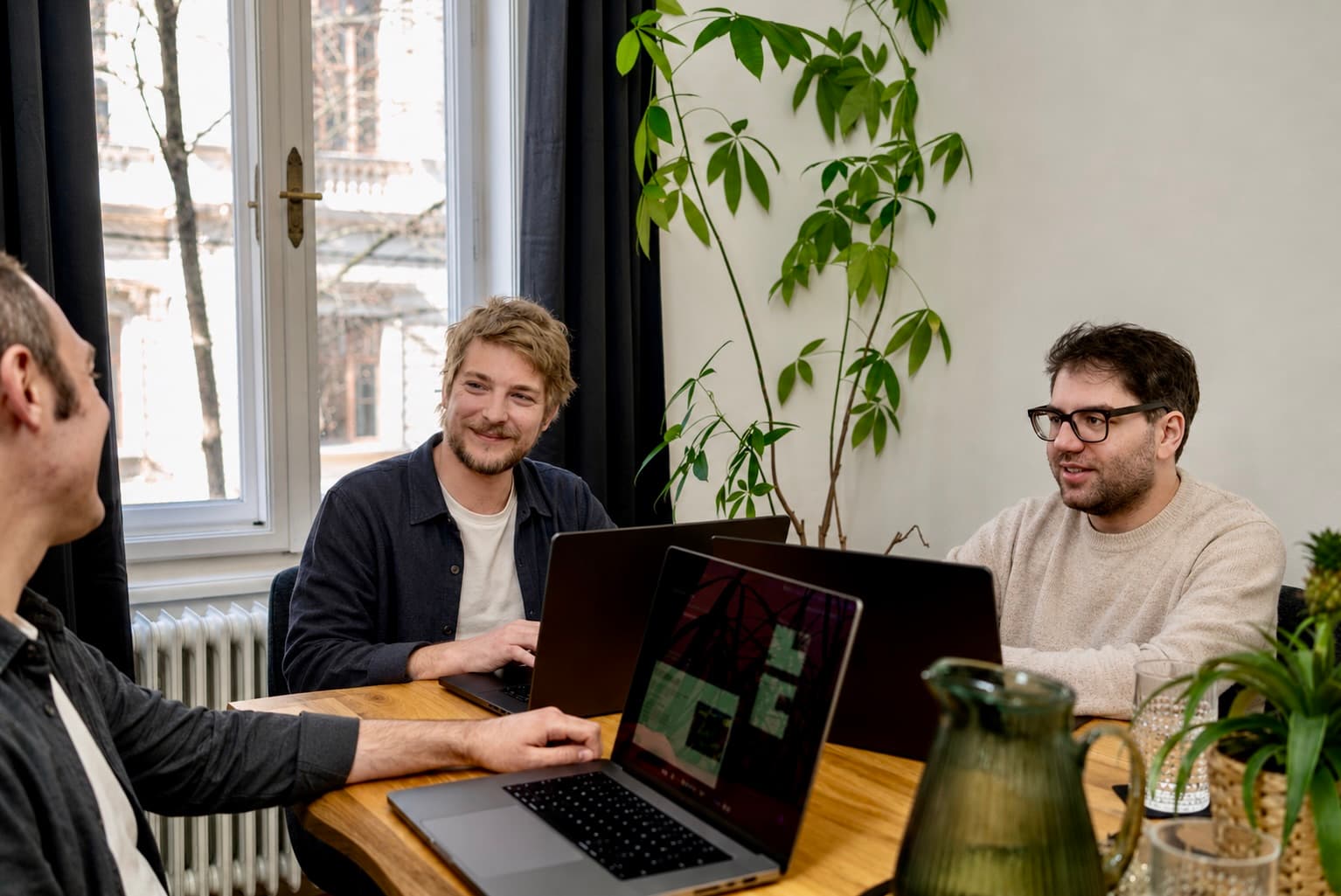 Zwei Teammitglieder arbeiten gemeinsam am Laptop auf der Studio-Couch
